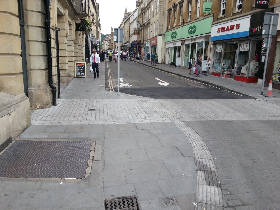 View from Flan OBrien's towards Westgate Street. Existing contraflow in place. Note tyre marks showing how tightly cars are taking the corner directly into the path of cyclists coming down the contraflow from Saw Close. Cars need a wider line of attack.